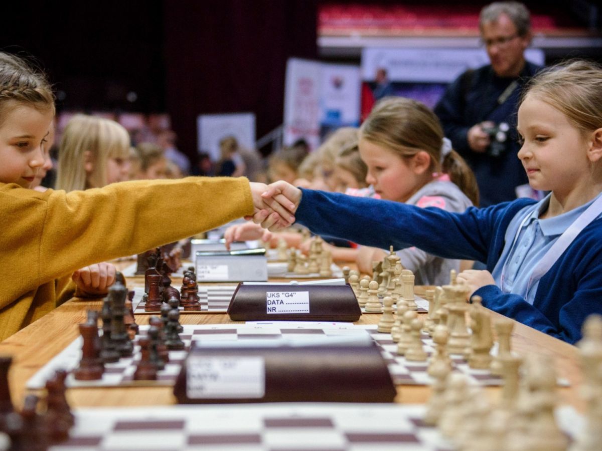młode szachistki zbijają piątkę nad szachownicą